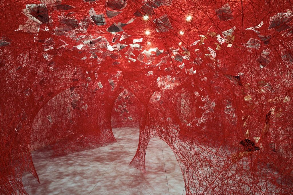 a full-room installation of red fiber and paper pages by Chiharu Shiota